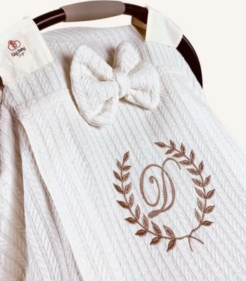 Krem örgü pike kumaştan, sade kapaklı, tül pencereli ve fiyonklu puset örtüsü.