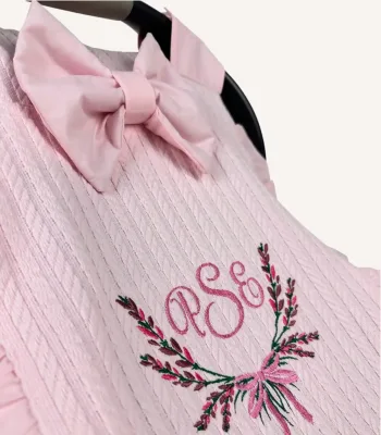 Pembe örgü pike kumaştan fırfırlı, kapaklı puset örtüsü; tül pencereli ve kişiselleştirilebilir nakış detaylı model.