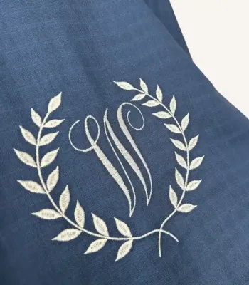 Denim mavi tek kat müslin kumaştan fırfırlı, kapaklı puset örtüsü; tül pencereli ve kişiselleştirilebilir nakış detaylı model.